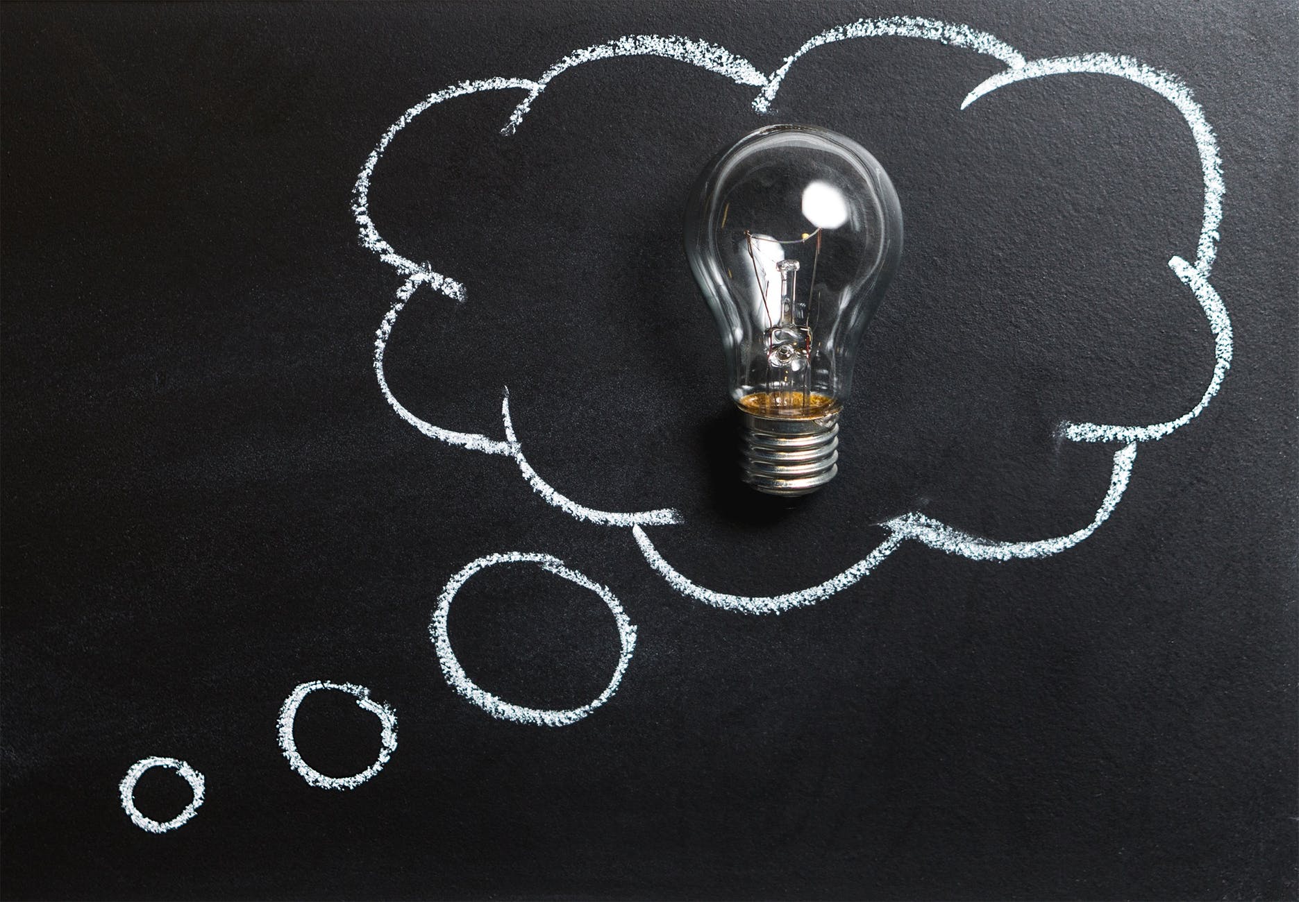 Image of a lightbulb in a thought bubble on a black board.