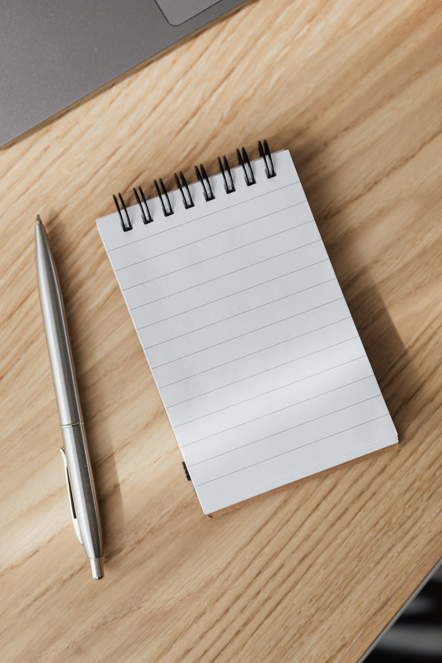 Image of a notepad and pen on a wooden desk.