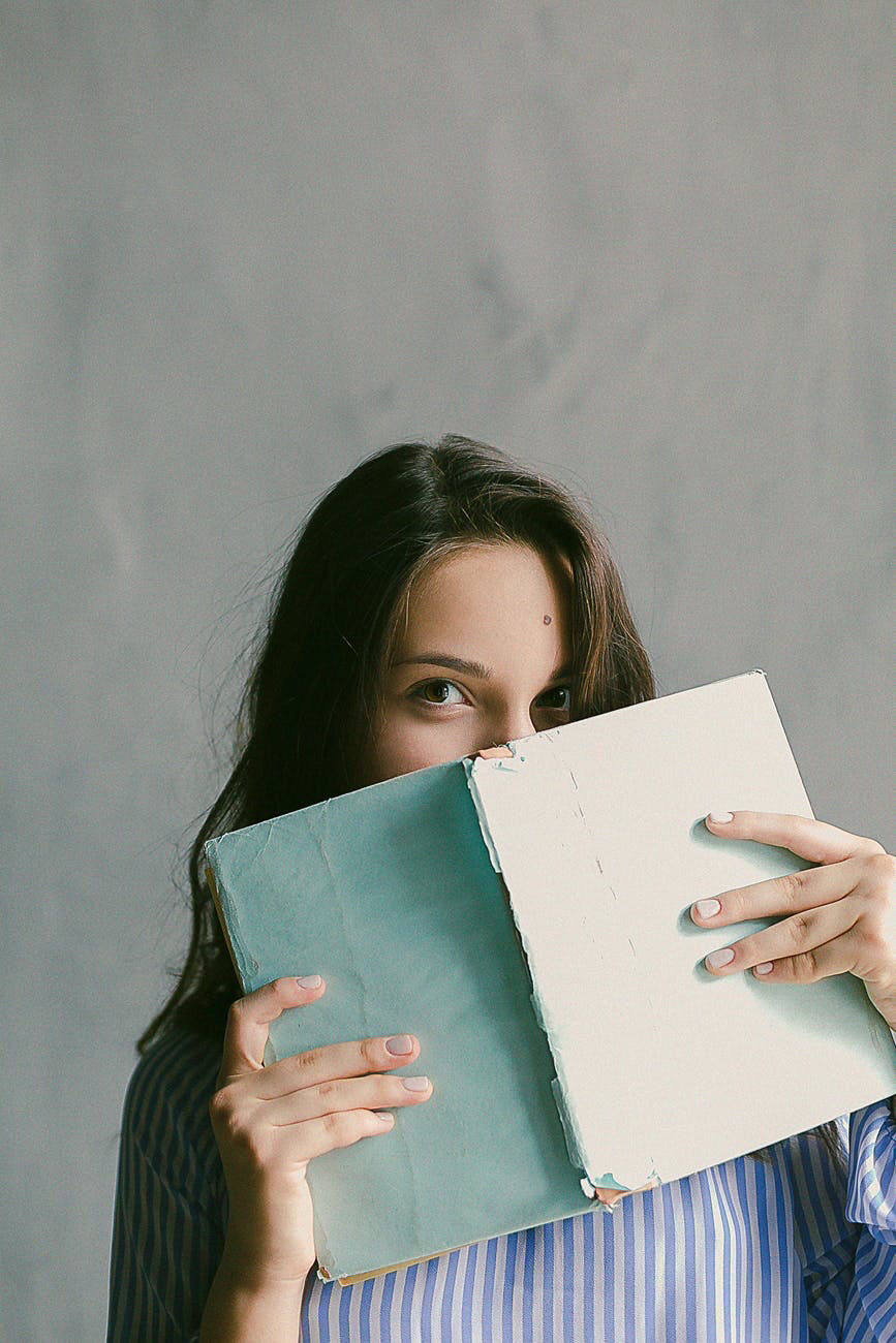 Woman holding a book that cover parts of her face