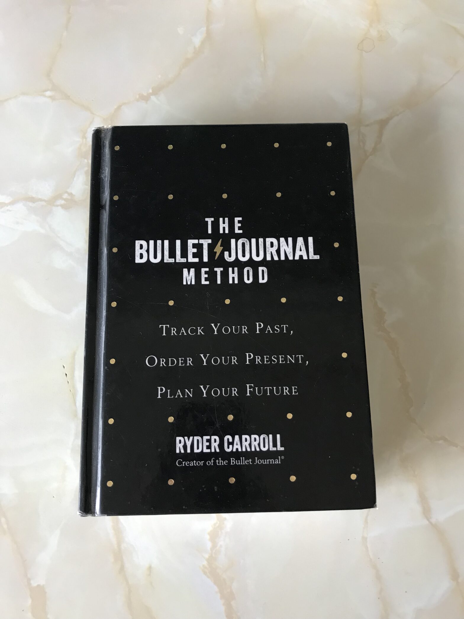 A picture of the book The Bullet Journal Method displayed on a marble background