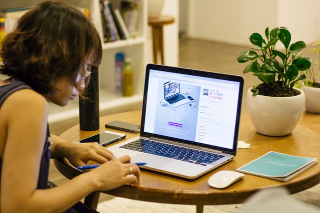 Student sitting in front of a table with a laptop, mouse and book on top of the table