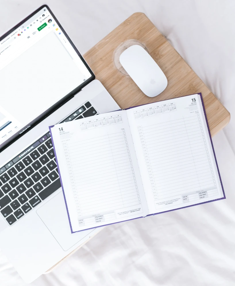 Image showing a laptop and mouse with an open planner covering parts of the keyboard.