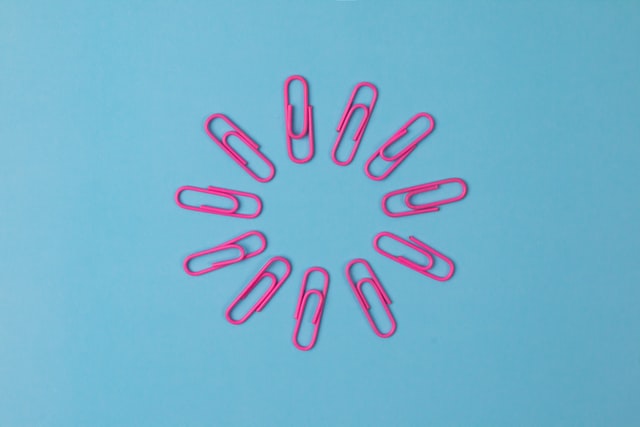 Image showing pink paper clips forming a circle, on a blue background.