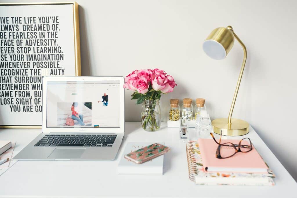 Image showing a desktop with a laptop, books, phone and flowers.