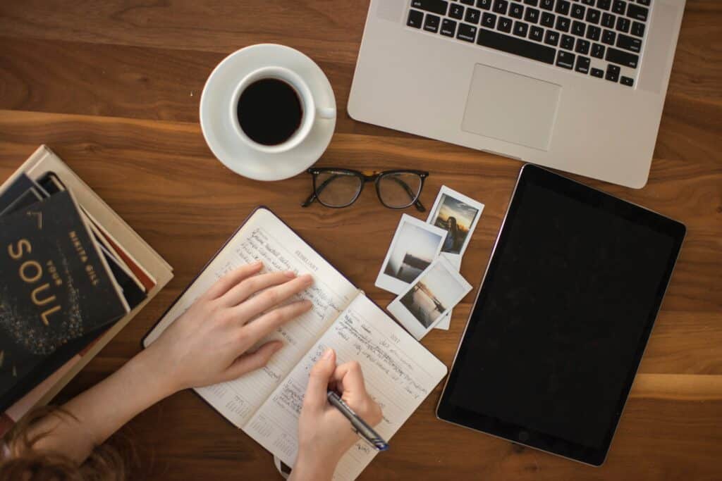 Image showing a person writing in a notebook on a desktop.