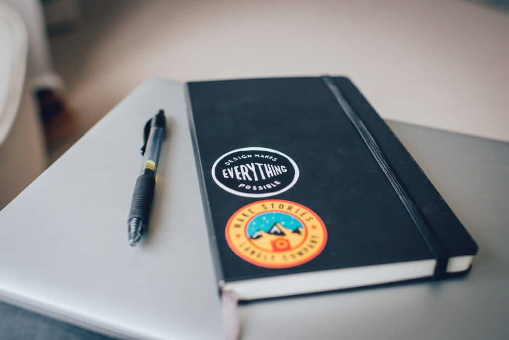 Image showing a black notebook and a gel pen.