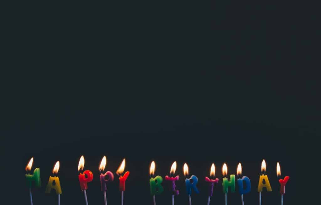 An image showing lit birthday candles spelling out happy birthday.