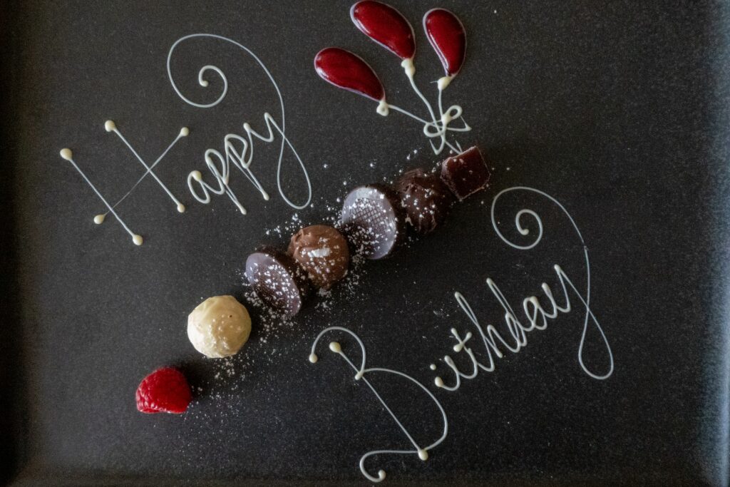 An image showing the words happy birthday written in frosting. There are some different pralines shown between the words.