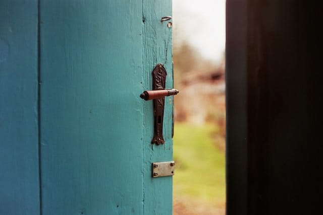 A teal wooden door slightly opened.