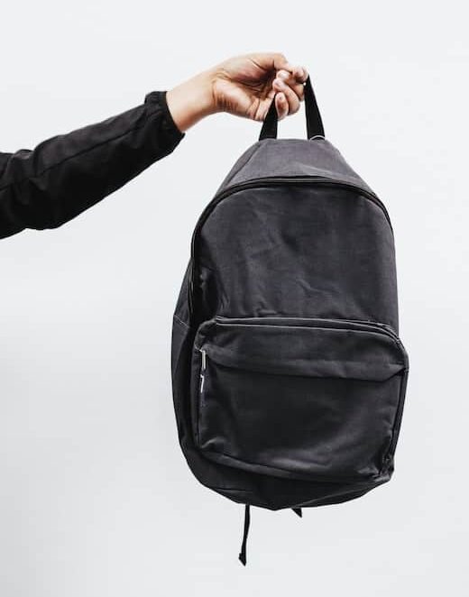 Person in black jacket holding black backpack