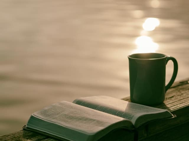 Image of a green ceramic mug beside a book.