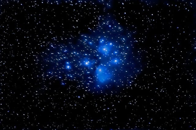 An image of a black night sky with the Pleiades showing